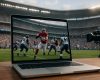A laptop displaying an NFL game scene with players in action on a football field