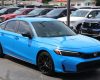 A blue Honda car parked among other vehicles in a dealership lot.