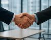 Close-up of two business professionals shaking hands in an office setting