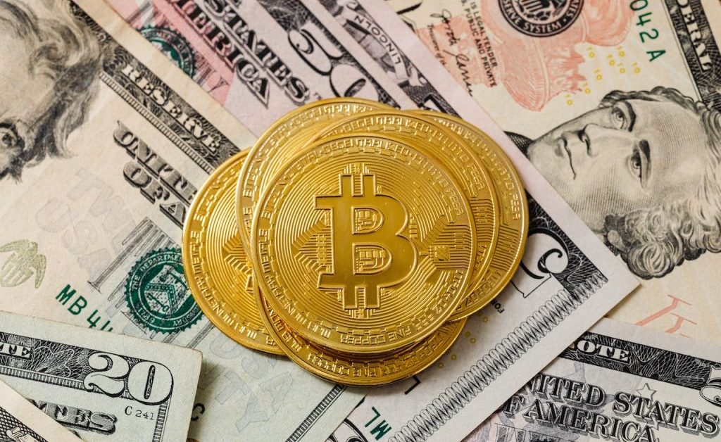 Gold Bitcoin coins on top of US dollar bills